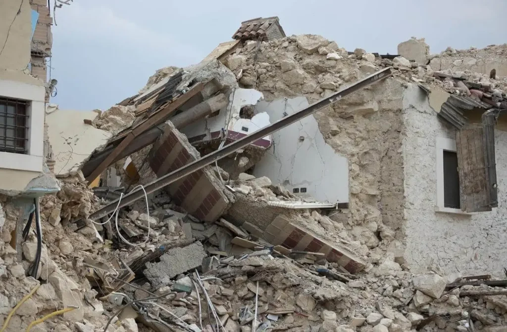 Collapsed building rubble after a powerful earthquake, representing global vulnerability to natural disasters.